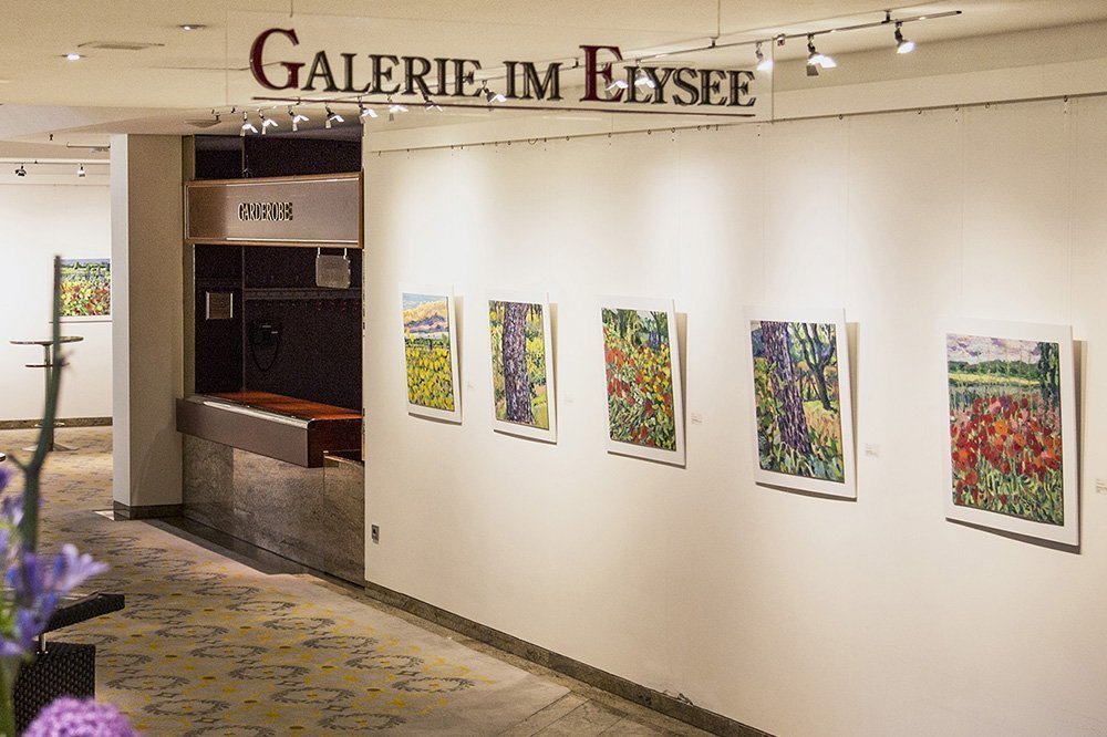 Raum der Galerie des Hotel Grand Elysée in Hamburg mit ein paar Bildern und der Garderobe im Hintergrund
