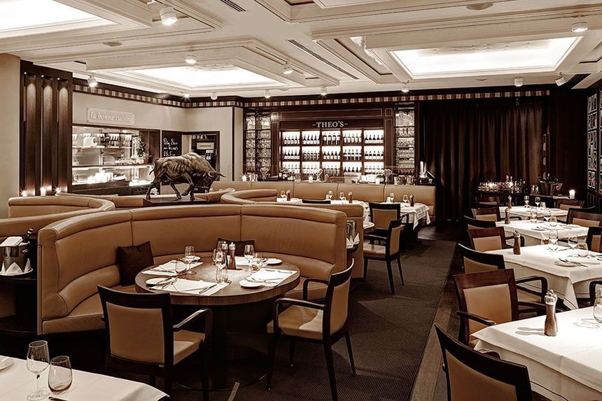 Runde Sitzbänke aus Leder sowie zahlreiche gedeckte Tische und Weinregal im THEO'S Steakrestaurant in Hamburg im Grand Elysée
