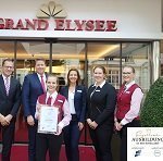 Menschengruppe mit der Auszeichnung "Exzellente Ausbildung" vor dem Grand Elysée Luxushotel in Hamburg