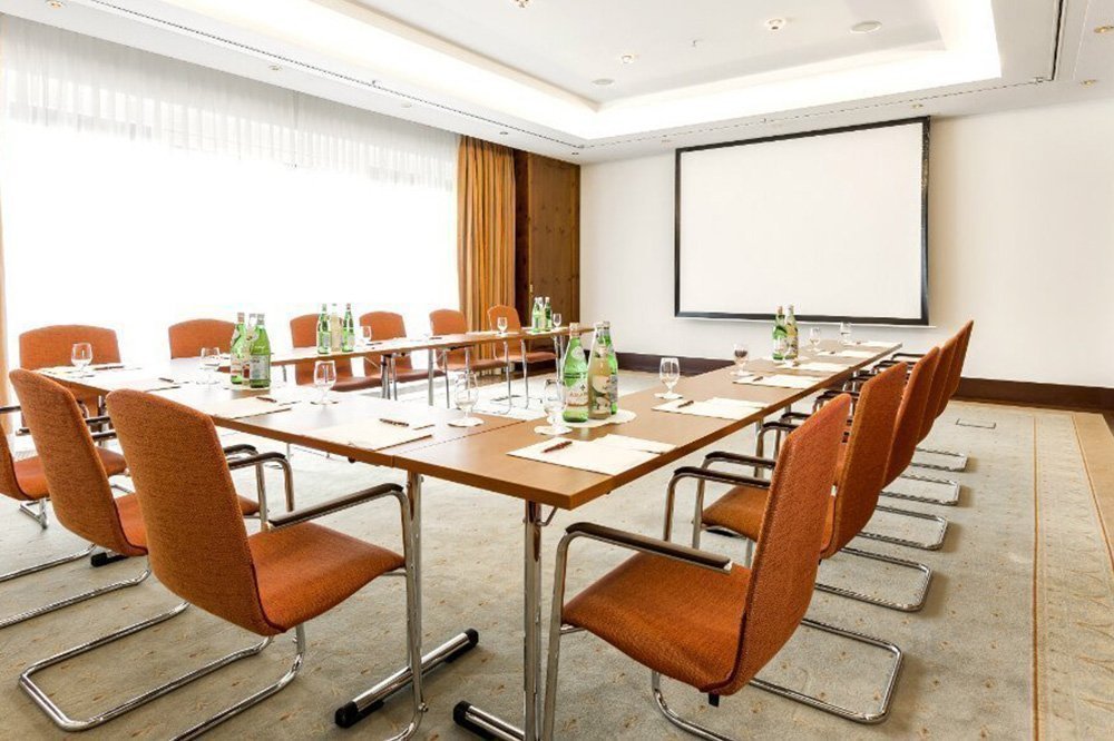 Tagungsraum "Pine Room" mit U-Förmig angeordneten Tischen, Getränken und einer großen Präsentationsleinwand
