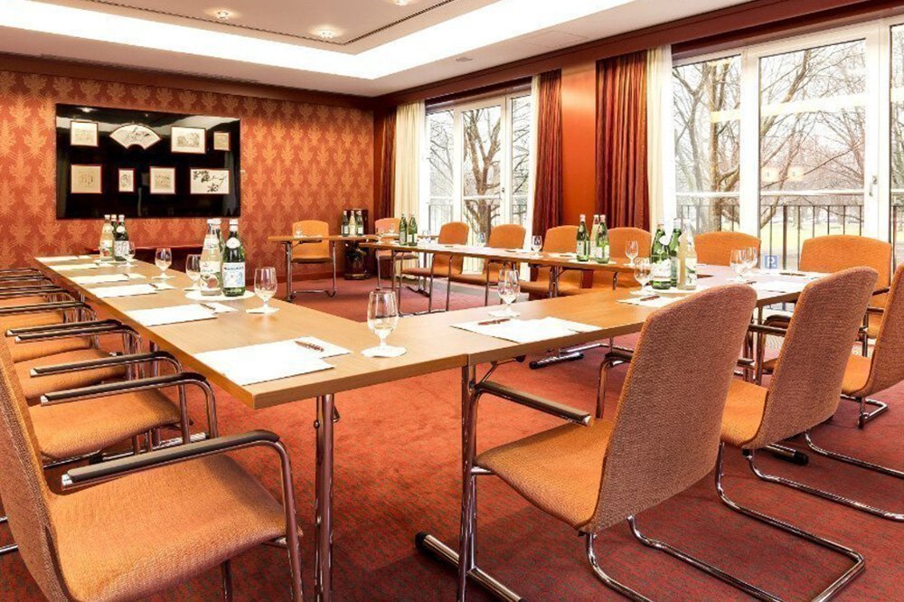 Meetingraum im Hotel Grand Elysée in Hamburg mit orange-roter Tapete und vorbereiteten Getränken auf den Tischen