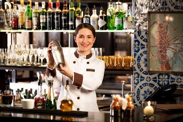 Barkeeperin der Oyster Bar schüttelt einen Cocktail während der Zubereitung für einen Gast