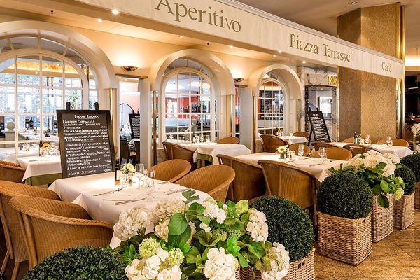 Blick auf die gedeckten Tische sowie Blumen im italienischen Restaurant Piazza Romana in Hamburg im Grand Elysée