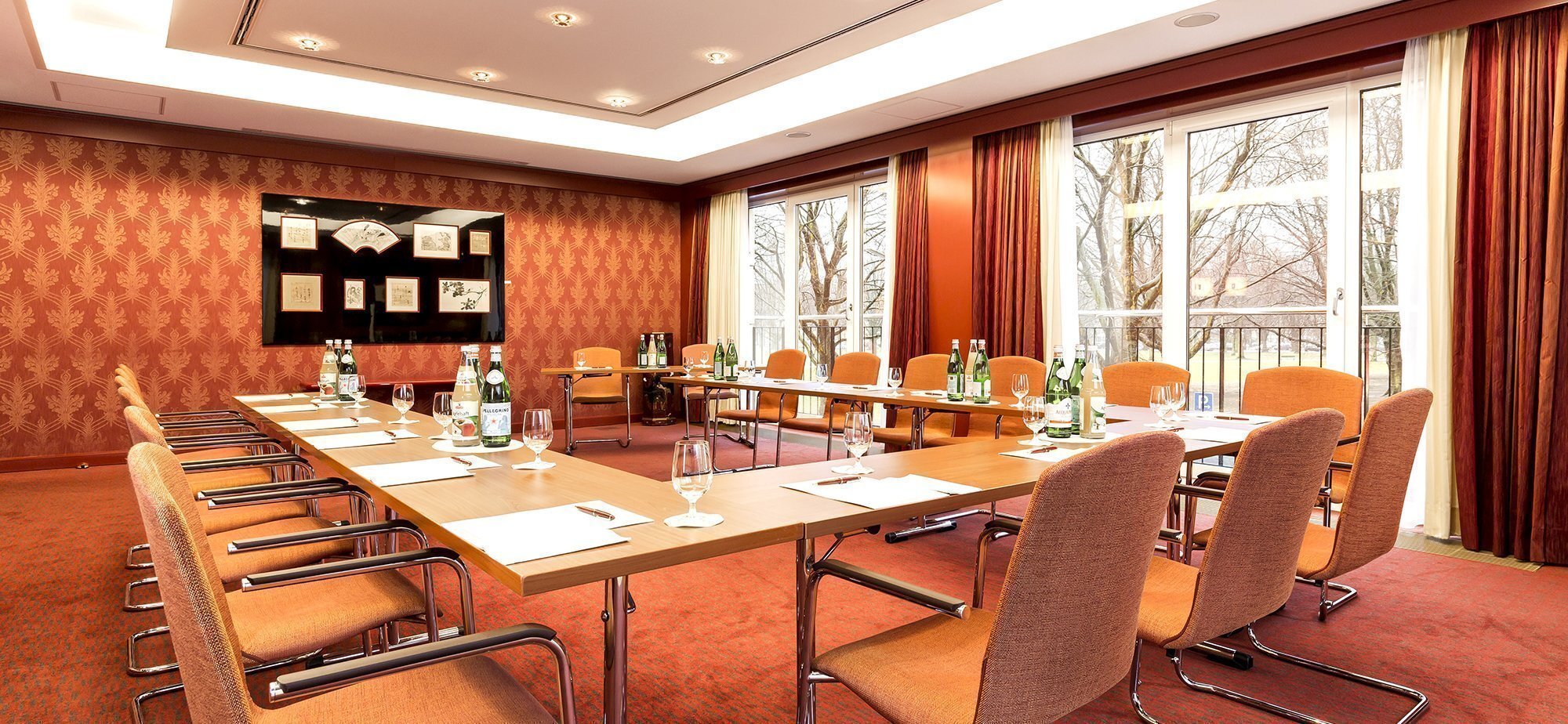 Hufeisenförmiger Konferenztisch mit orangenen Teppichboden