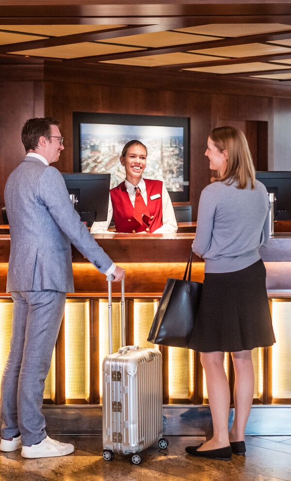 Rezeption des Grand Elysée Hamburg mit zwei Gästen beim Check-in