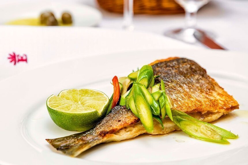 Angerichtete Dorade angerichtet mit Gemüse und einer Limette
