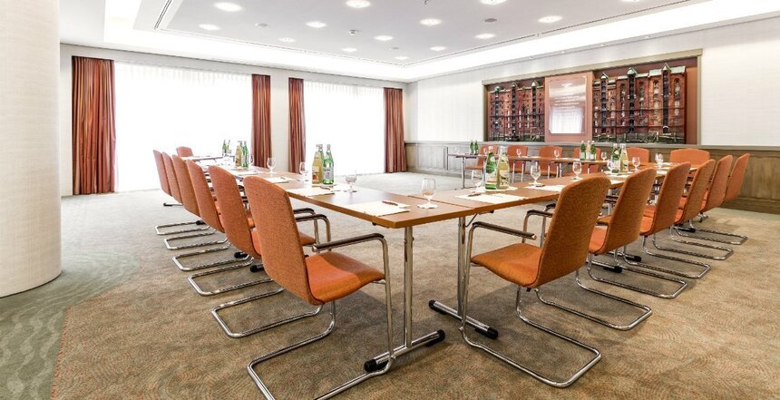 Kleinerer Hufeisenförmiger Konferenztisch mit Getränken auf den Tischen